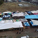 Top view of market stalls set up beneath colourful tarps.