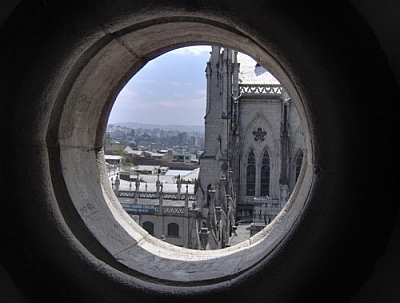 View of Quito through a round window of the Basilica del Voto Nacional.