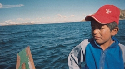 Young boy rowing a boat to Isla del Sol, Bolivia.