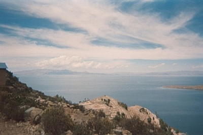 Gorgeous scenery of the vast Lake Titicaca beneath a wide open sky streaked with wispy clouds.