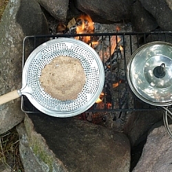 Cooking our trail flatbread on our hand toaster, which we simply place on a grill instead of holding.