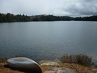 An upturned canoe sits on shore at Boundary Lake while canoe camping in Killarney.