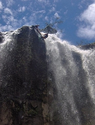 Climbing down the ledge of the last set of falls while repelling in Baños.