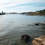 Large rocks protrude here and there from a small bay, and little islands dot the horizon.