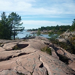 Dark cracks in the pink granite seem to move forward towards the pine-tree-lined shore of Georgian Bay.
