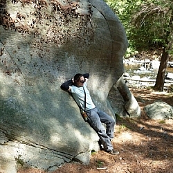 Leaning on a huge boulder at Grundy Lake Park while hiking in Ontario