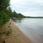 A long, narrow beach, a boat parked in the distance.
