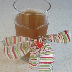 Glass of kombucha tea wrapped in a red, white, and green striped holiday bow.