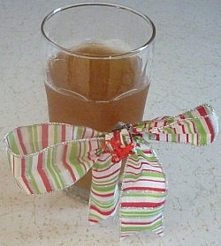 Glass of kombucha tea wrapped in a red, white, and green striped holiday bow.