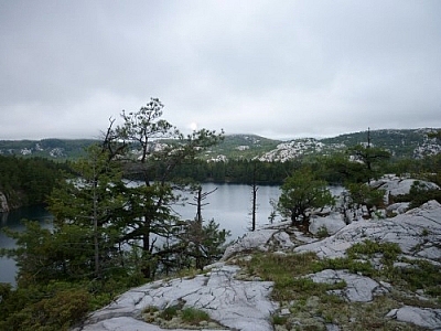 Sun and clouds over a lake and mountains while trekking Killarney's La Cloche Silhouette loop trail.