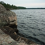 Lake Nipissing, partially blocked by a boulder on the left, is dark grey and choppy.