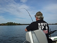 Fisherman reeling in a cast, wearing a funny yet appropriate t-shirt.