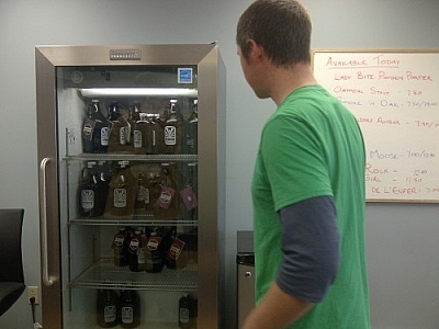 A Stack Brewing employee stands before a stocked beer fridge.