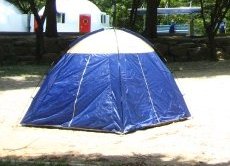 A blue tent — a useful travel tool indeed — set up on a sandy camping pad.