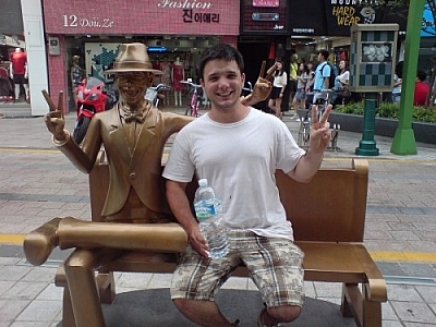 Travel with a buddy! Here, a statue sits on a pedestrian bench in Busan, South Korea, and a CouchSurfer sits next to it in the same pose.