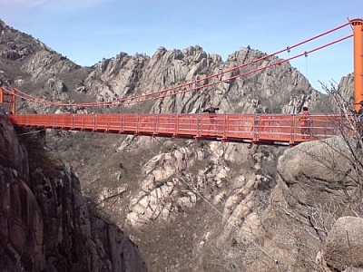 Red suspension bridge crossing a chasm high up in the mountains on a Wolchulsan hike.