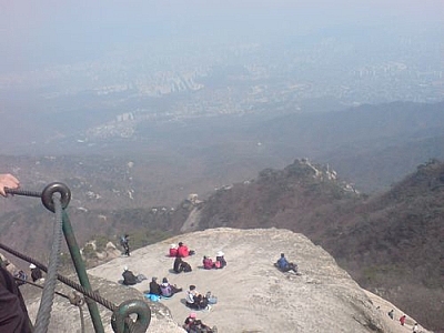 People resting on a steep mountain ledge at Bukhansan National Park.