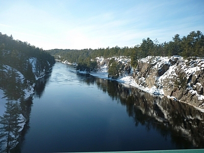 A bit of snow covers the rocky riverside, the water surface still on this cold winter's day.